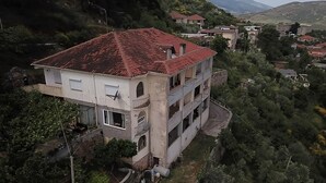 A multi-story building with a red roof, surrounded by greenery and hills. - Vila across Tepelena (Tepelenë)