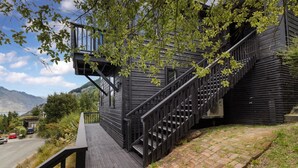 A wooden staircase leading to a deck with a view of a mountain and a lake.