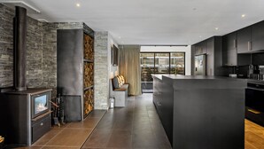 A modern kitchen with a central island, dark cabinetry, and a stone wall.