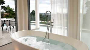 Une salle de bain moderne avec une baignoire sur pieds, une douche et de grandes fenêtres donnant sur l’extérieur.
