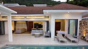 Une maison moderne dotée d’une piscine, d’un espace salon extérieur et d’un mur en pierre.