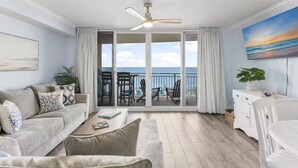A spacious living room with a large sliding glass door leading to a balcony with a view of the ocean.