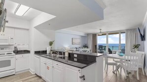 A modern kitchen with white cabinetry, a black countertop, and a view to the outside.