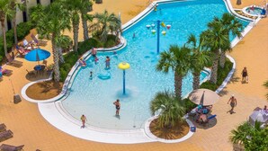 A multi-level pool area with palm trees, lounge chairs, and a water slide.