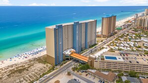 A coastal hotel with multiple high-rise buildings, a beach, and a parking lot.