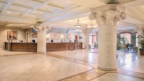 Un hall d’entrée spacieux, doté d’un comptoir de réception, de grandes colonnes et d’un lustre.