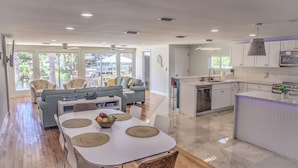 A modern kitchen with white cabinets, a central island, and a dining area with a white table and chairs. - New Listing! Dockside Palms Weeki Wachee-Spring Fed Canal-Boat Friendly!  (Spring Hill)
