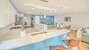 A modern kitchen with a marble countertop, a built-in sink, and a dining area with a table and chairs. - New Listing! Dockside Palms Weeki Wachee-Spring Fed Canal-Boat Friendly!  (Spring Hill)