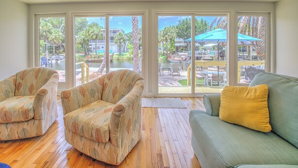 A room with a large sliding glass door leading to an outdoor patio area. There are two patterned armchairs and a green sofa with a yellow pillow. - New Listing! Dockside Palms Weeki Wachee-Spring Fed Canal-Boat Friendly!  (Spring Hill)