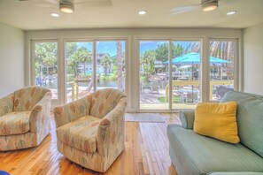 A room with a large sliding glass door leading to an outdoor patio area. There are two patterned armchairs and a green sofa with a yellow pillow. - New Listing! Dockside Palms Weeki Wachee-Spring Fed Canal-Boat Friendly!  (Spring Hill)