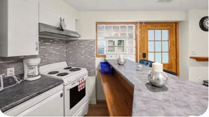 A modern kitchen with white cabinets, a gas stove, and a marble countertop.