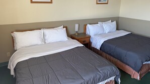 Ein Hotelzimmer mit zwei Betten, einem Nachttisch und zwei gerahmten Bildern an der Wand.
