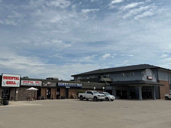 A building with a sign for 'Oriental Grill' and 'High Liquor' on the ground floor, a parking lot, and a 'Lobby' sign on the building.