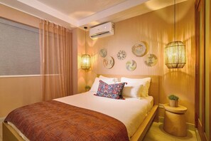 A hotel room with a large bed, a bedside table with a plant, a wall-mounted air conditioner, and decorative wall art. - ®{Tulum~Experience}@Downtown +Pool+View+Penthouse (Santo Domingo)