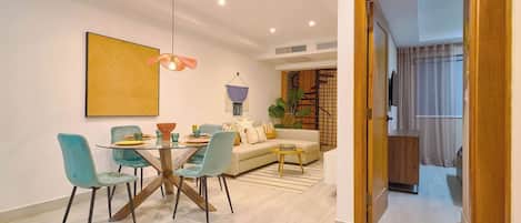 A modern living room with a dining area, a sofa, a coffee table, and a hanging light fixture.