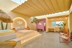 A modern hotel room with a pool, a bed, a staircase, and a view of the city.