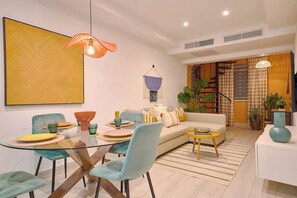 A modern living room with a glass dining table, a sofa, and a staircase leading to an upper level. - ®{Tulum~Experience}@Downtown +Pool+View+Penthouse (Santo Domingo)