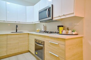 A modern kitchen with white cabinets, a built-in microwave, a gas stove, and a small oven. - ®{Tulum~Experience}@Downtown +Pool+View+Penthouse (Santo Domingo)