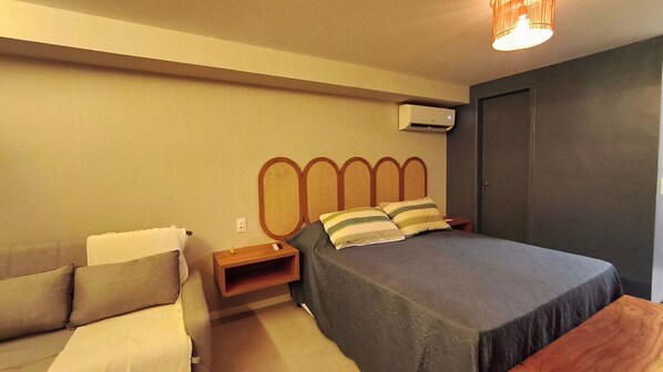 A bedroom with a bed, bedside table, and a wall-mounted air conditioner. - Serrambi Beach Flat - Porto de Galinhas (Ipojuca)