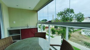 A balcony with a dining table and chairs, a small kitchen area, and a view of the surrounding neighborhood.