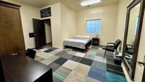 A bedroom with a bed, a desk, a chair, a window, and a mirror. - Utah Prep Basecamp (Hurricane)