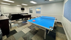 A room with a ping pong table, a foosball table, a sofa, and a TV on the wall. - Utah Prep Basecamp (Hurricane)