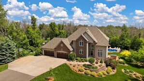 A two-story house with a garage, a swimming pool, and a well-maintained lawn.