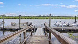 A wooden dock leading to a calm river with boats docked on the right. - Charming Cottage-resort style pool, pickleball (Hanahan)
