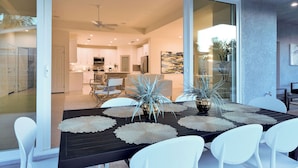 Un comedor moderno con una mesa negra, sillas blancas y delicados manteles individuales decorativos.