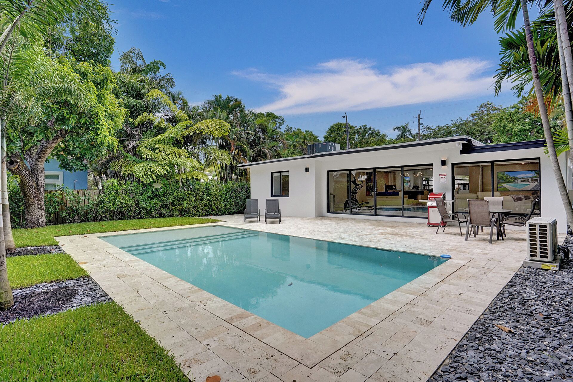 A modern house with a swimming pool, patio furniture, and lush greenery.