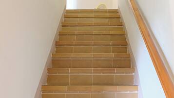 A staircase with brown tiles and a wooden handrail.