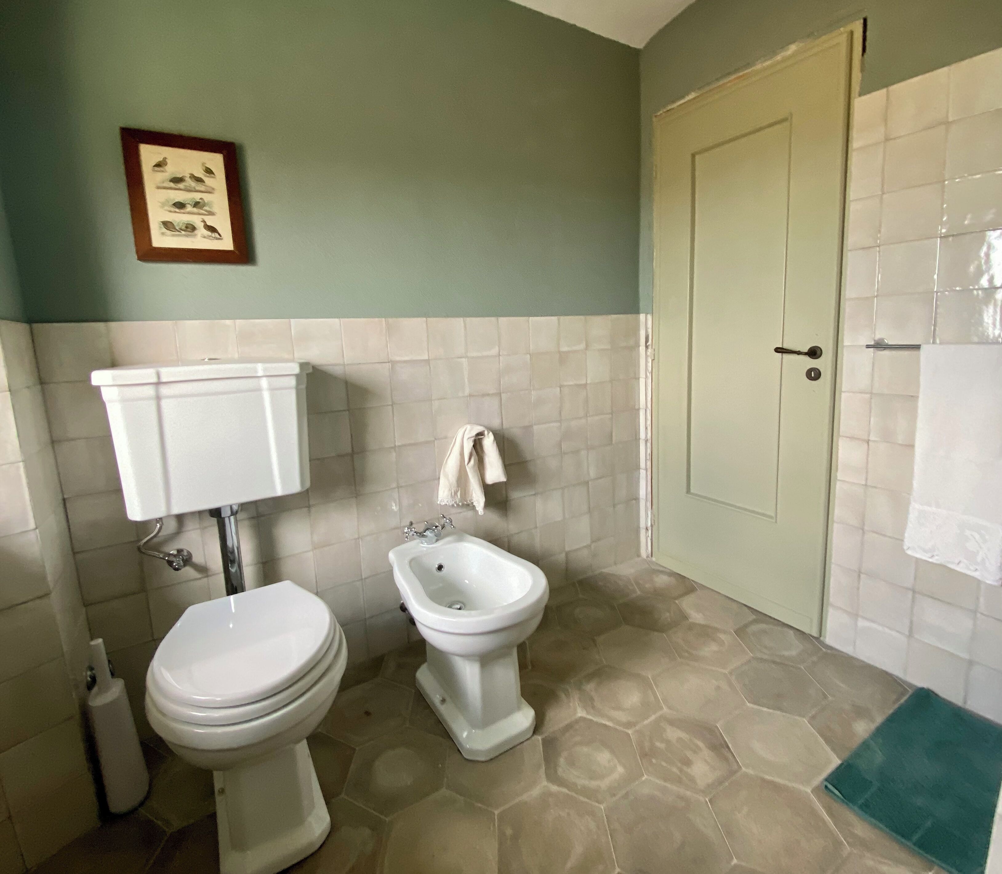 Een badkamer met een toilet, bidet en een deur.