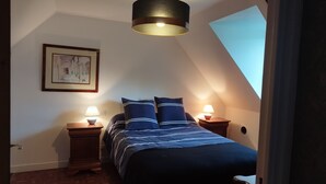 A bedroom with a bed, two bedside tables with lamps, a framed picture on the wall, and a sloped ceiling. - Gite Lann er Viline (Camors)