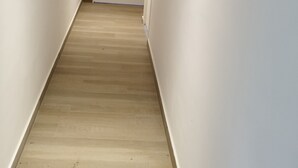 A hallway with wooden flooring, white walls, and two framed pictures. - Gite Lann er Viline (Camors)