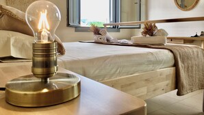 Une chambre d’hôtel avec un lit, une table de chevet avec une lampe, une fenêtre, un miroir et une vue sur l’extérieur.
