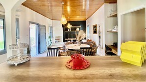 Un coin repas avec un plafond en bois, une table ronde entourée de chaises et un objet décoratif rouge posé sur la table.