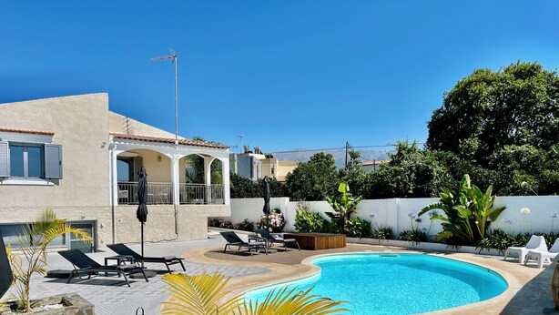 Un espace aménagé au bord de la piscine, avec des chaises longues, une petite table et une piscine.
