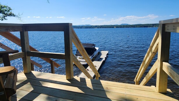 A wooden dock extending into a lake with a boat docked at the end. - Spacious, modern, home by the lake! (Northville)