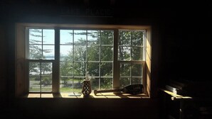A window with a view of trees and a sign above it that reads "LAKE PLACID". - Spacious, modern, home by the lake! (Northville)