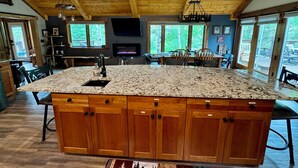 A spacious kitchen with a large island, wooden cabinets, and a stone countertop.