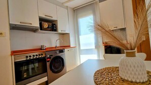 A compact kitchen with a washing machine, oven, and microwave.
