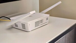 A white portable Wi-Fi router with a long antenna on a white surface.