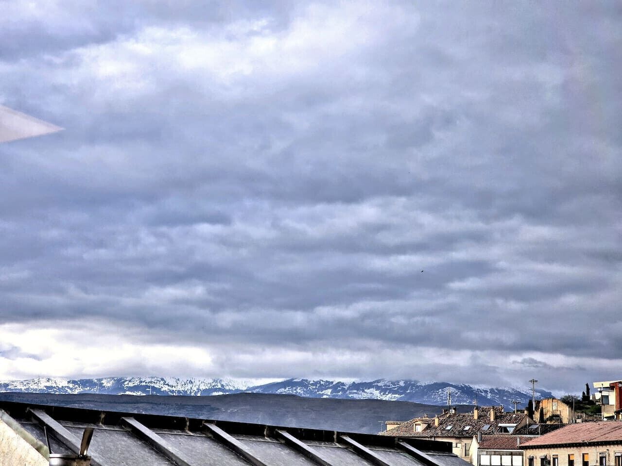 Blick auf eine Berglandschaft mit schneebedeckten Gipfeln unter einem bewölkten Himmel.