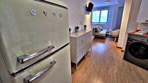 A compact kitchen with a white refrigerator, a washing machine, and a grey cabinet.