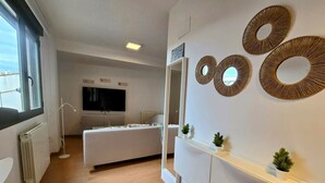 A modern hotel room with a large bed, a TV, a mirror, and decorative wall art.