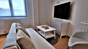 A modern living room with a sofa, a coffee table, a TV, and a chair.