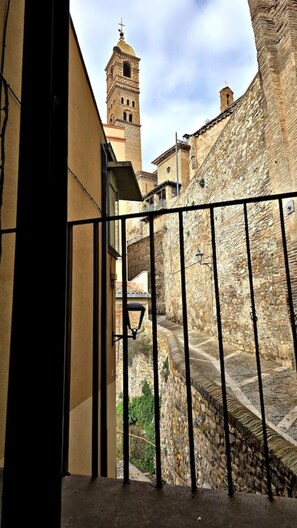 Un balcón con vistas a una pared de piedra histórica y una torre.