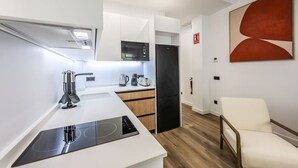 Eine moderne Küche mit Induktionskochfeld, einer Mikrowelle, einer Kaffeemaschine und einem Kühlschrank.