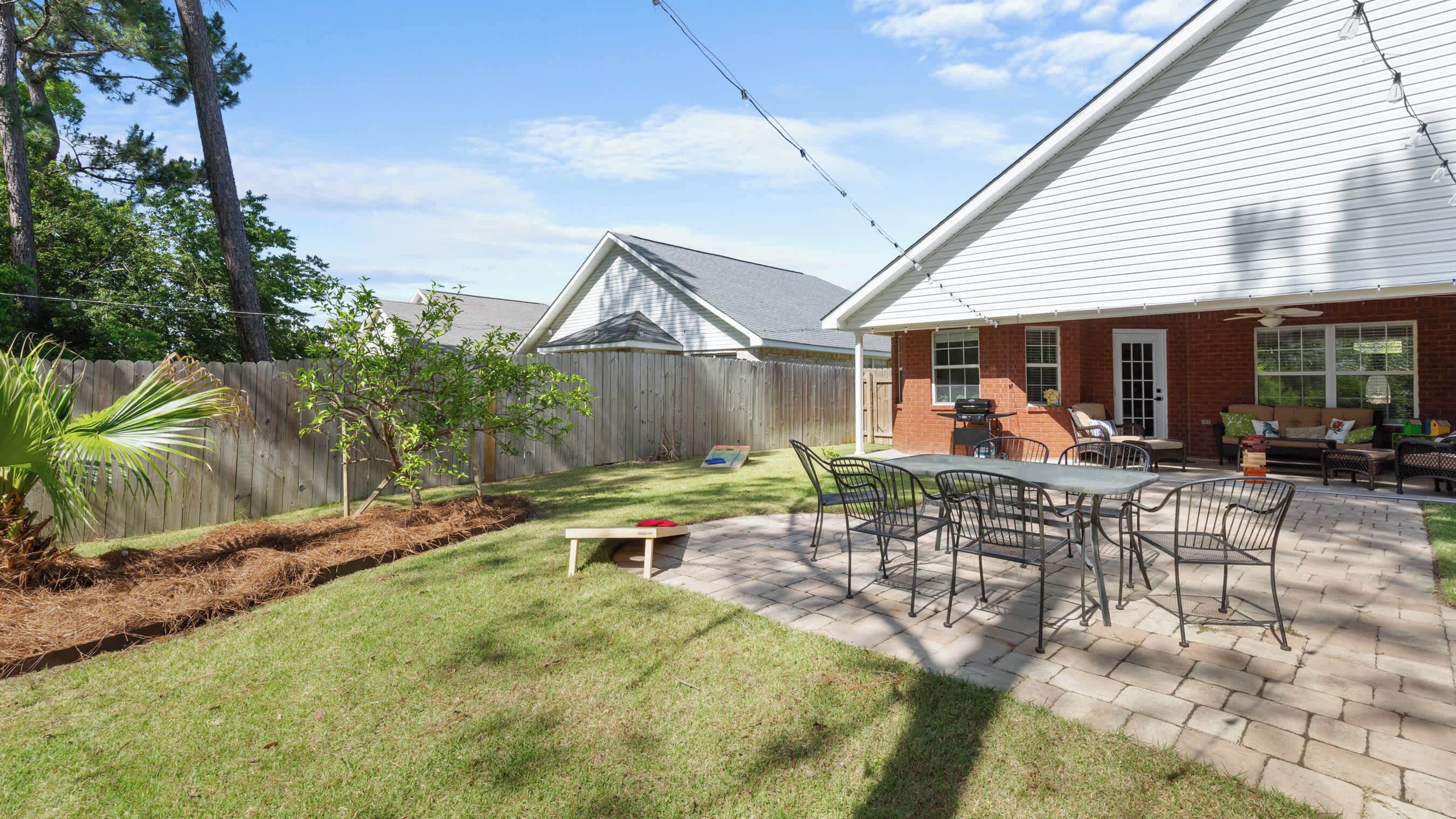 A backyard with a patio area, a small lawn, and a wooden fence.
