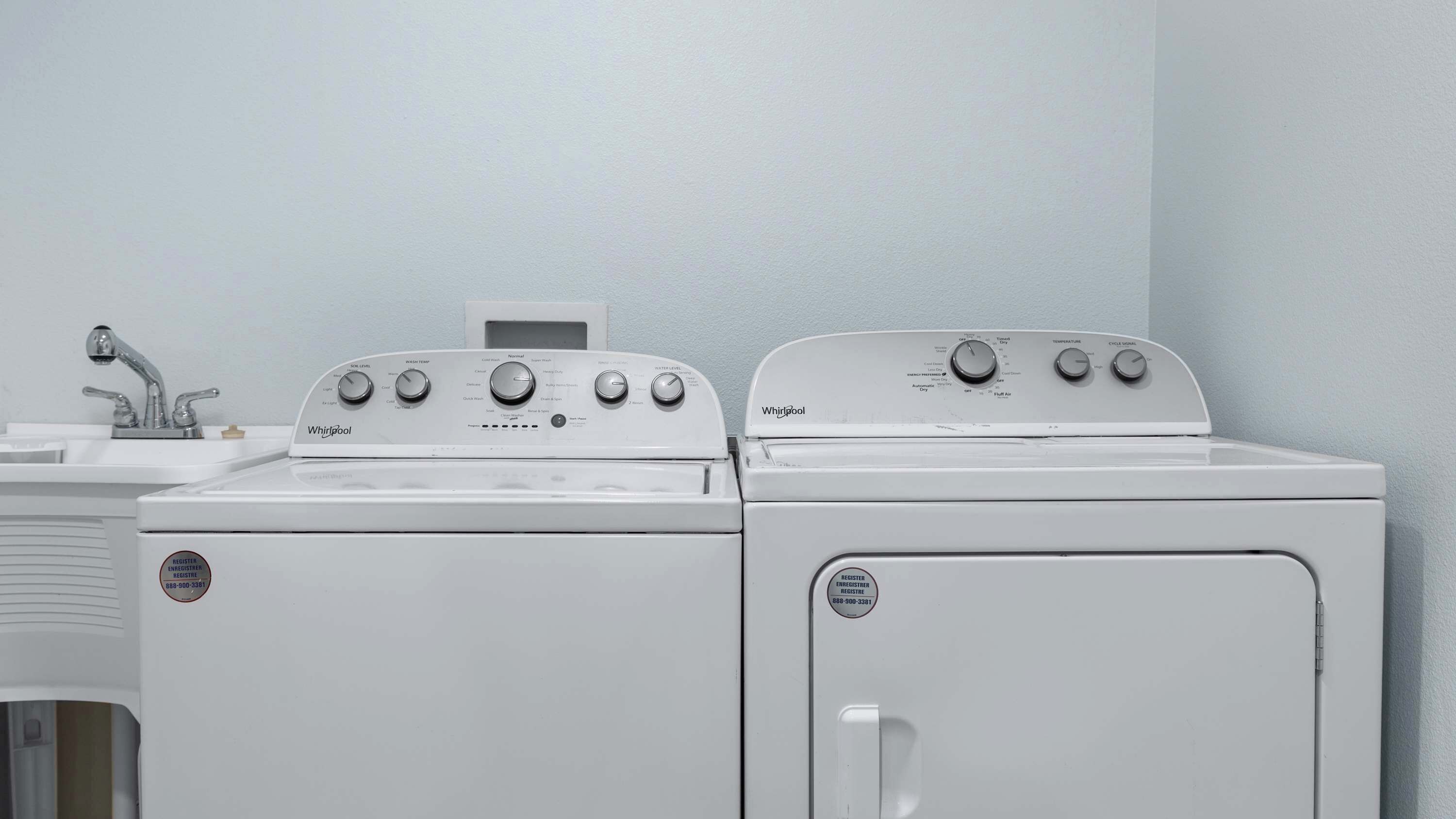 Une buanderie équipée de deux sèche-linge Whirlpool et d’un évier.